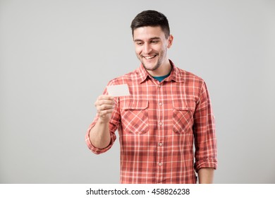 Young Man Reading Business Card Isolated On Gray Background