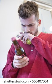 Young Man Reading Label On Beer Bottle In Cafe