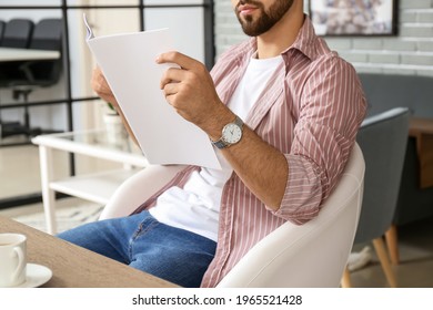 Young Man Reading Magazine At Home