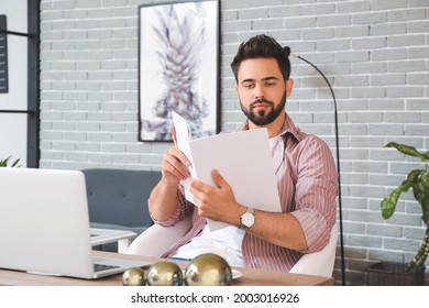 Young Man Reading Magazine At Home