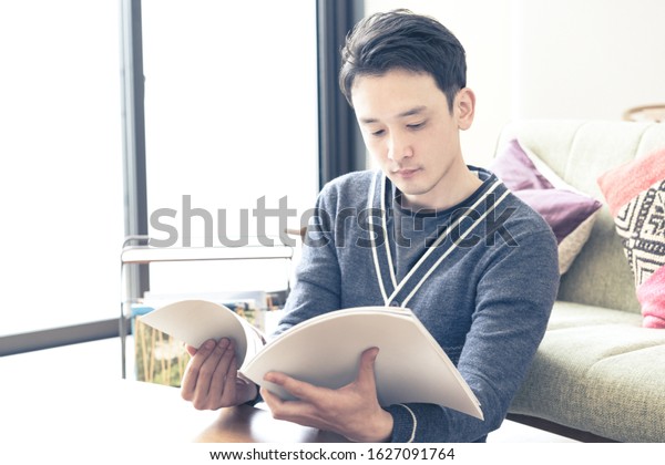 Young man\
reading a magazine in the living\
room