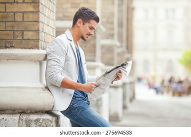 Young Man Reading Newspaper On The City Street