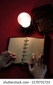 Young Man Reading On A Blank Page Of A Vintage Leather Book Under The Low Light Condition With A Yellow, Light Bulb.