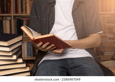 A young man reading a red book in a cozy library. The concept of knowledge, education, and literature. Ideal for learning, studying, and academic themes.
