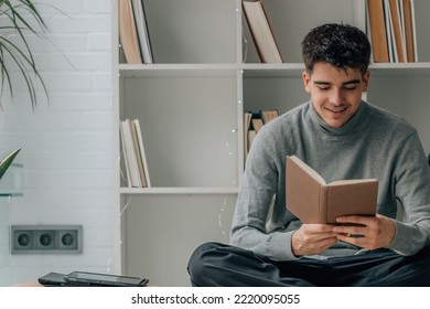 Young Man Reading Textbook At Home Or Library