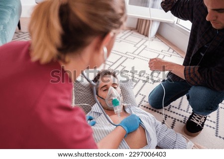 Young man receiving emergency medical attention from a doctor at home. Concept: health care, first aid, emergency