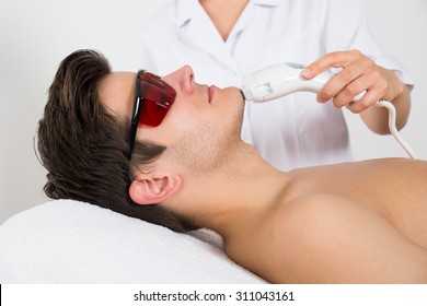 Young Man Receiving Laser Hair Removal Treatment At Beauty Center