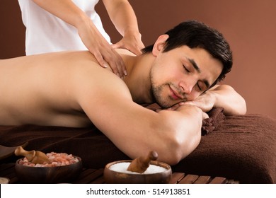 Young Man Receiving Shoulder Massage From Therapist In Spa