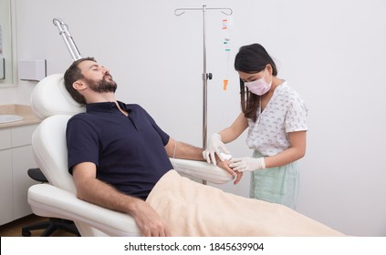 Young man receiving vitamin IV infusion drip in hospital or beauty salon. Healthcare and medicine concept