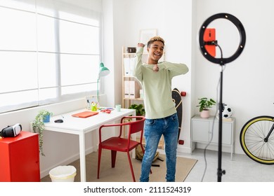 Young Man Recording Dance Video Tutorial For Social Media With Smart Phone In Youth Room - Influencer Teenager Boy Creating New Content For His Blog While Streaming Online - New Digital Trend Concept