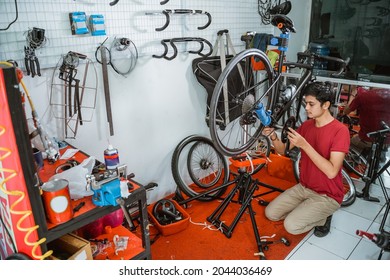Young Man In Red Clothes Working Assembling Bicycle Crank Set With Tools