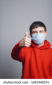 Young Man In Red Sweatshirt Wearing A Protective Mask On His Face And Showing A Finger Up, Concept Health, Gesture Optimistic Outlook In Future, Survivor Behavior