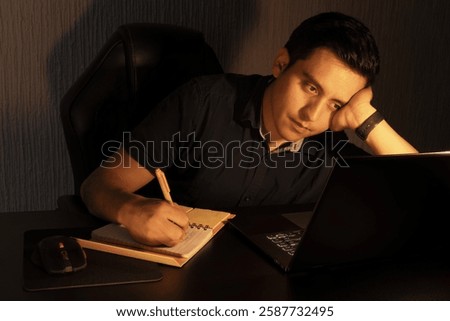 Young Man Reflecting While Working Late at Night on a Laptop