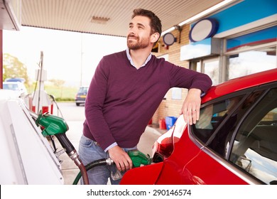 Young man refuelling a car at a petrol station