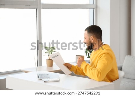 Young man with refund form at table in room