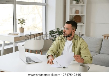 Young man with refund form at table in room