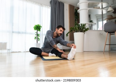 Young Man Rehabilitation Exercise At Home After Car Crash Accident. Recovery Workout Of Young Guy With Yoga Training Poses For Stretching The Muscles. Physical Therapy Exercising