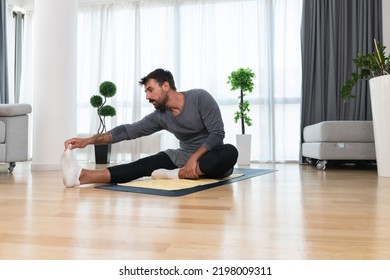 Young Man Rehabilitation Exercise At Home After Car Crash Accident. Recovery Workout Of Young Guy With Yoga Training Poses For Stretching The Muscles. Physical Therapy Exercising