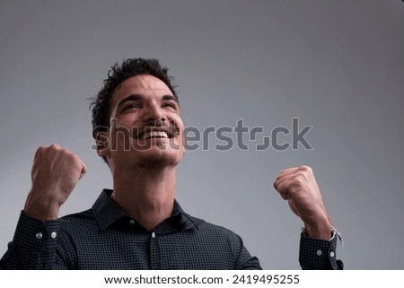 A young man rejoices with raised arms, masculine and virile energy. Is it a sports victory, work success, or a hefty bet win? Or love? Definitely great news