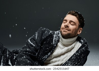 A young man relaxes in a cozy winter sweater, embracing the gentle snowfall around him. - Powered by Shutterstock