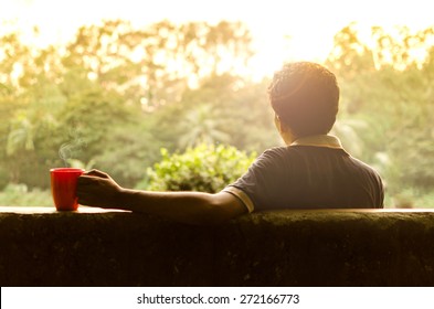 Young man relaxing in a garden having hot coffee in afternoon - Powered by Shutterstock