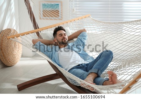 Young man relaxing in hammock at home