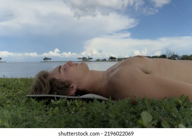 A Young Man Relaxing. He's Laying On His Back On A Yoga Mat. He Is Doing Savasana Which Is Also Known As Corpse Pose.