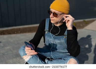 Young Man Relaxing On A Bench In Downtown District Listening To Music. High Quality Photo