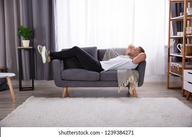 Young Man Relaxing On Sofa In Living Room