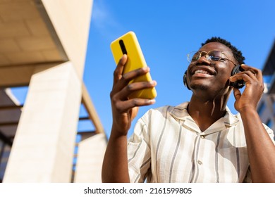 Young Man Relaxing Outdoors Listening To Music Using Phone And Headphones. Copy Space.