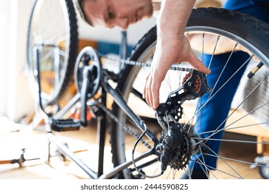 Young man repairing a bicycle at home. Mechanic serviceman repairman installing assembling or adjusting bicycle gear on wheel in workshop. - Powered by Shutterstock