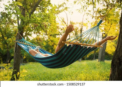 Young man resting in comfortable hammock at green garden - Powered by Shutterstock