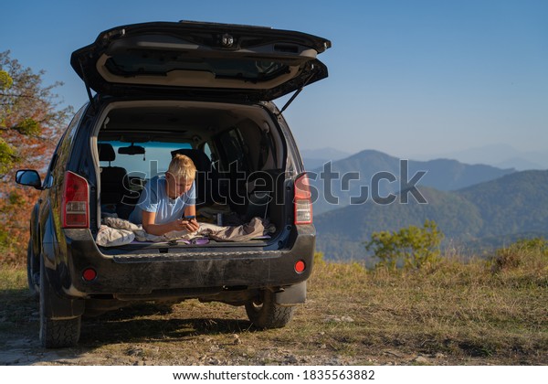 Young man resting in
nature with an off-road vehicle resting in the trunk of a car.
Communicates on a mobile phone using cellular communication and the
Internet.