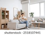 Young man resting on sofa in room with operating air conditioner