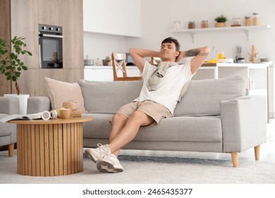 Young man resting on sofa in kitchen - Powered by Shutterstock