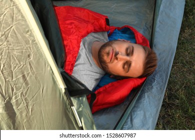 Young Man Resting In Sleeping Bag Inside Camping Tent, Above View