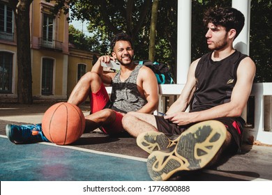 young man rests after the basketball game and uses his smartphone with his friend - Shutterstock ID 1776800888