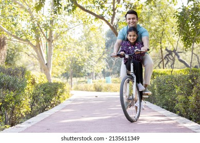 Young man riding bicycle with daughter at park
 - Powered by Shutterstock