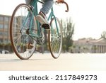 Young man riding bicycle on city square, closeup