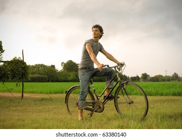 Young man riding a bike in a field - Powered by Shutterstock