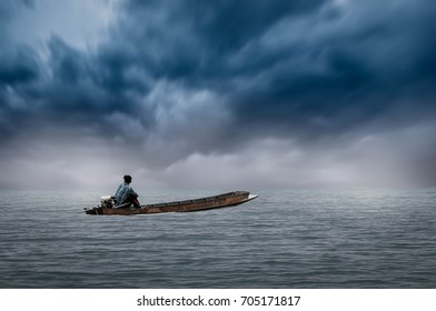 A young man riding a boat on a stormy cloudy day.