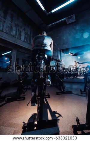young man riding an exercise bike. The guy is exercising on a stationary bike. View with the mirror