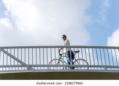 Young Man Riding Fixed Gear Bike On City Bridge