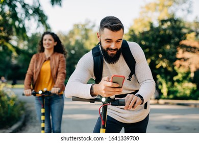 Young man riding his electric scooter and looking at mobile phone. - Shutterstock ID 1641339700