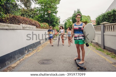 Young man riding on skate and holding surfboard