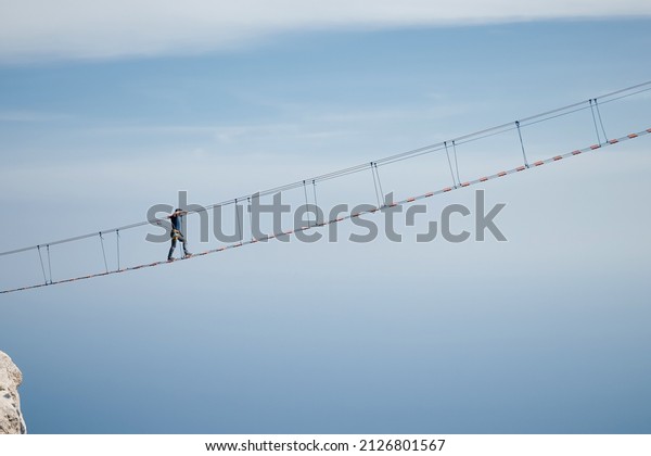 The young\
man risking life go on rope bridge on\
sky