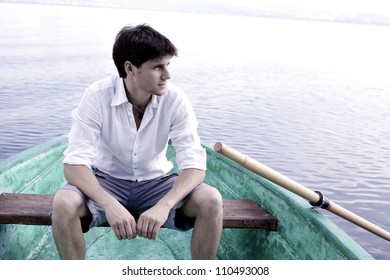 young man rowing a green boat on a lake