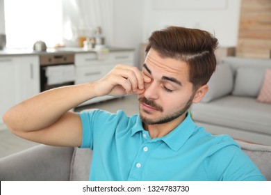 Young Man Rubbing Eye At Home. Annoying Itch