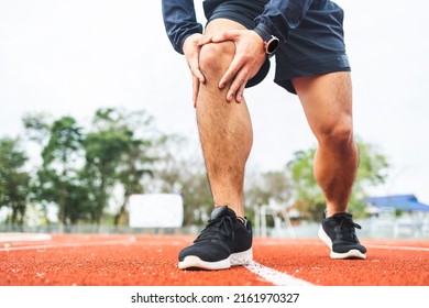 Young Man Runner Has Sore Knee Because He Ran Too Long. Male Exercising Until The Injury. Overtrained. Young Sport Man Accident Running On Track