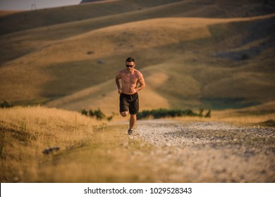 Young man runner running on a mountain road. Jogger training workout in fitness shoe. Healthy lifestyle and sport concept.  Motion blur and selective focus.